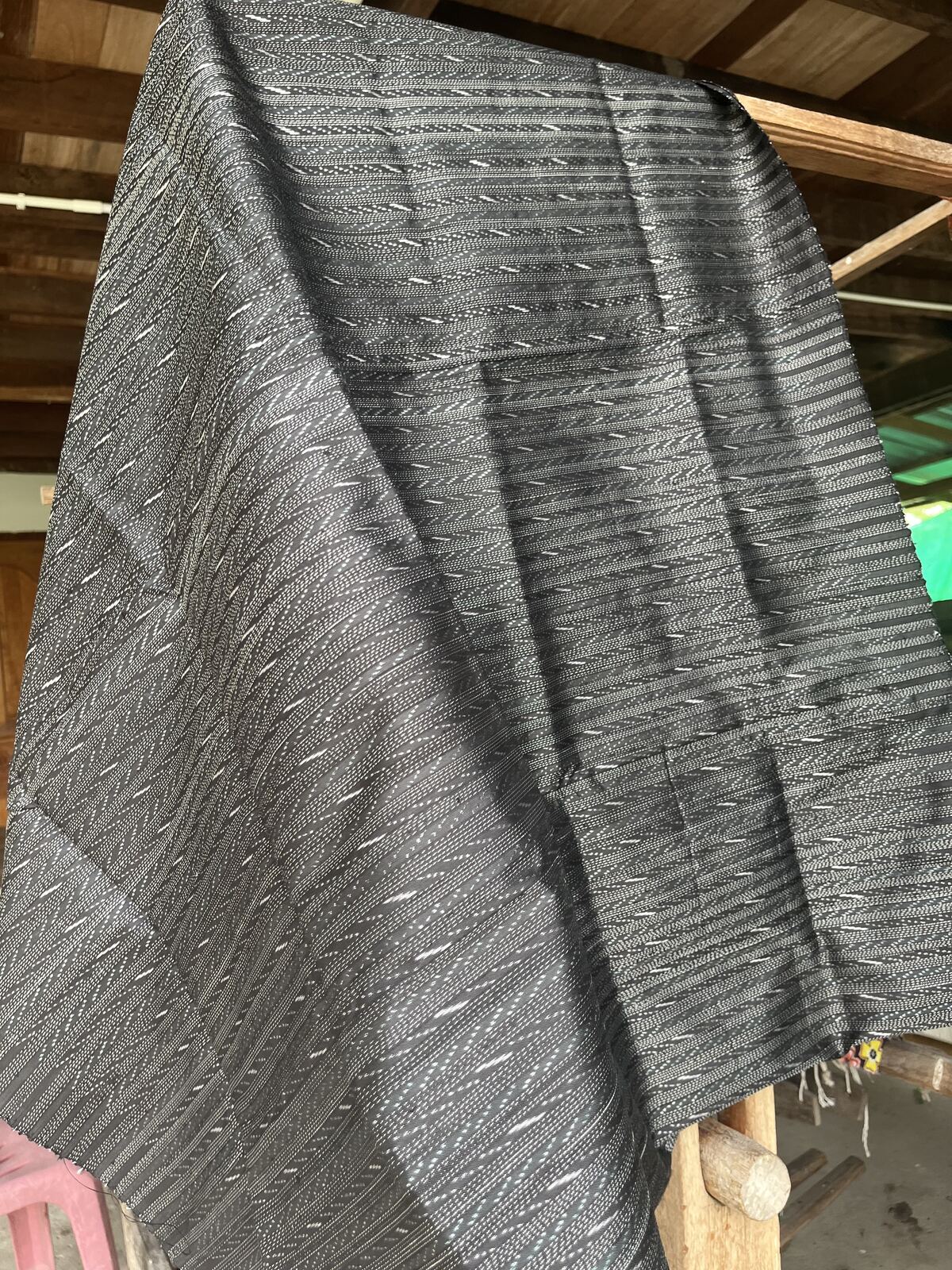 Black hol silk draped over a rail, the figure surfacing where the light rakes it